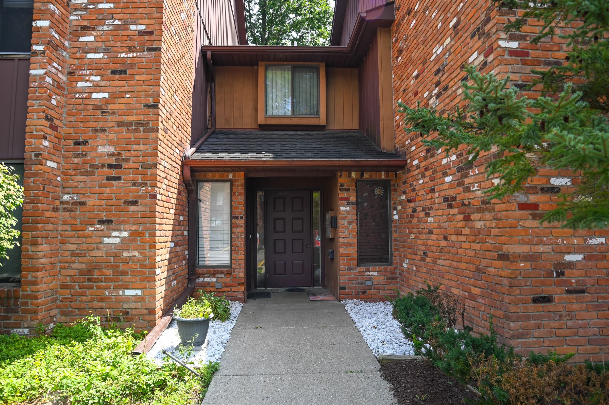 Brick apartment entrance with established garden beds