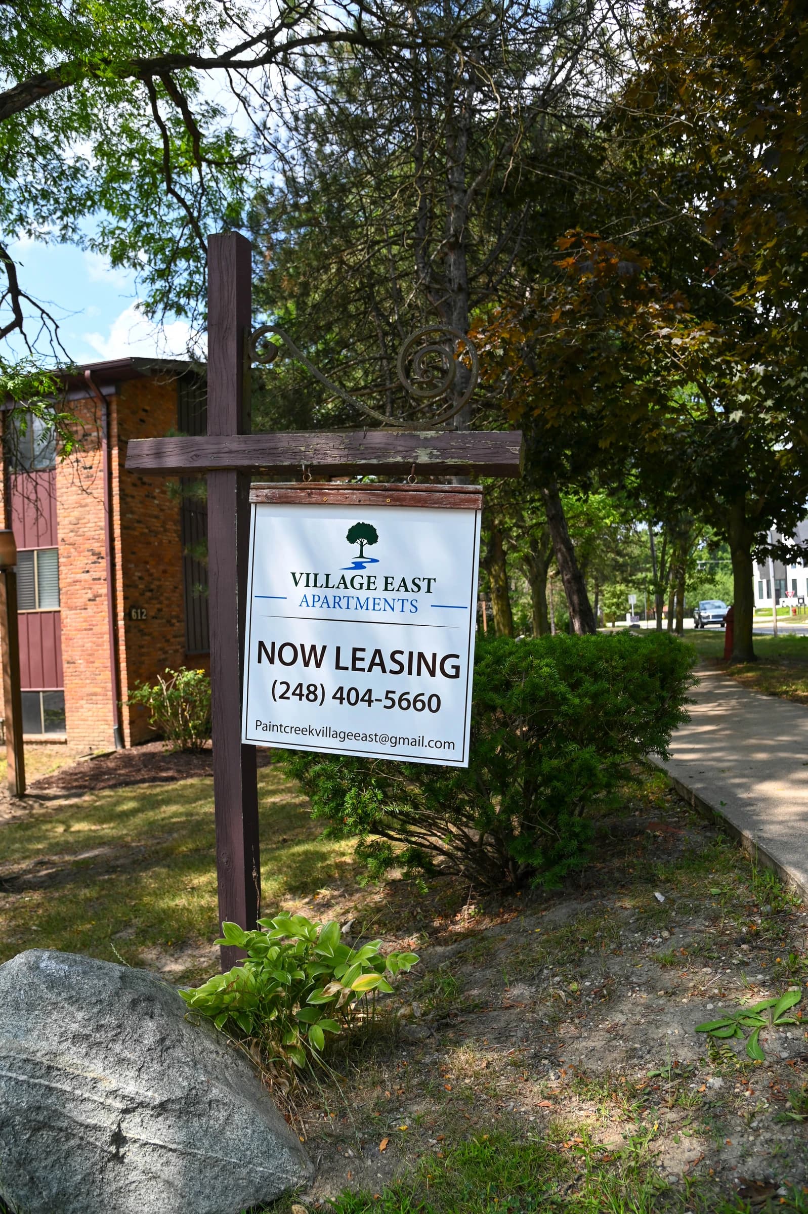 Village East Apartments entrance sign beneath the trees